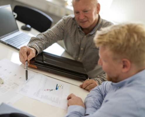 Møde om vedligeholdelsesplan med tegninger på bordet