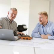 To rådgivere diskuterer byggeprojekt foran bærbar computer