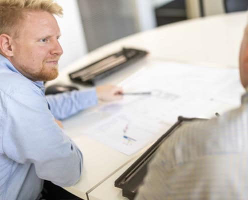 Byggerådgiver gennemgår byggetegninger ved bordet