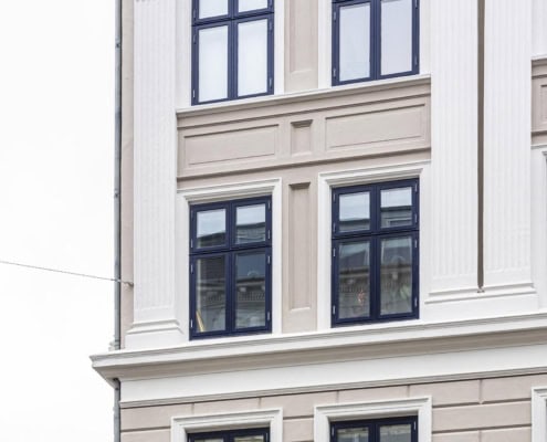 Detaljeret udsnit af hvid facade med mørke vinduesrammer