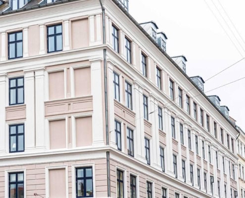 Renoveret hjørnefacade i lyserød puds med nye vinduer