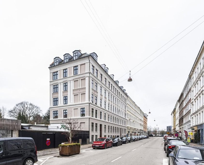 Gadebillede med hjørneejendom og byliv